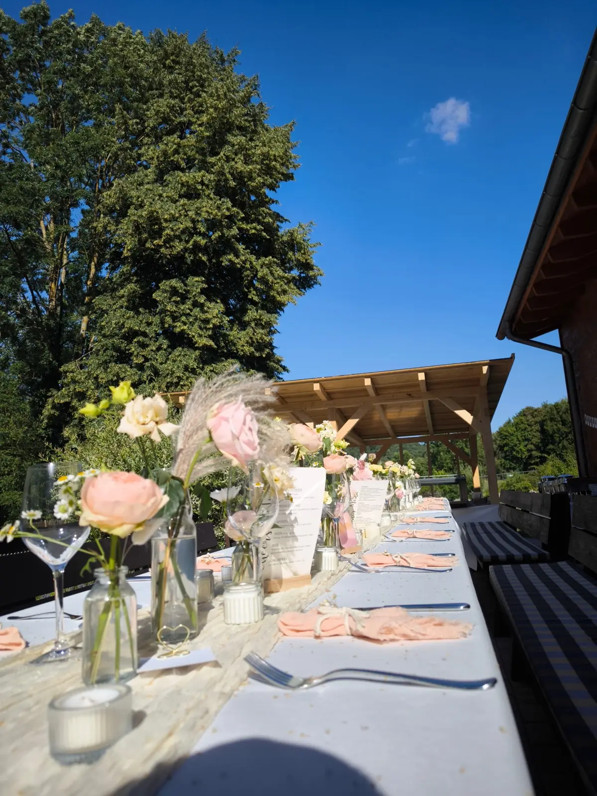 Festlich gedeckte Tafel mit Blumen und Menükarten bei einer Feier im Freien